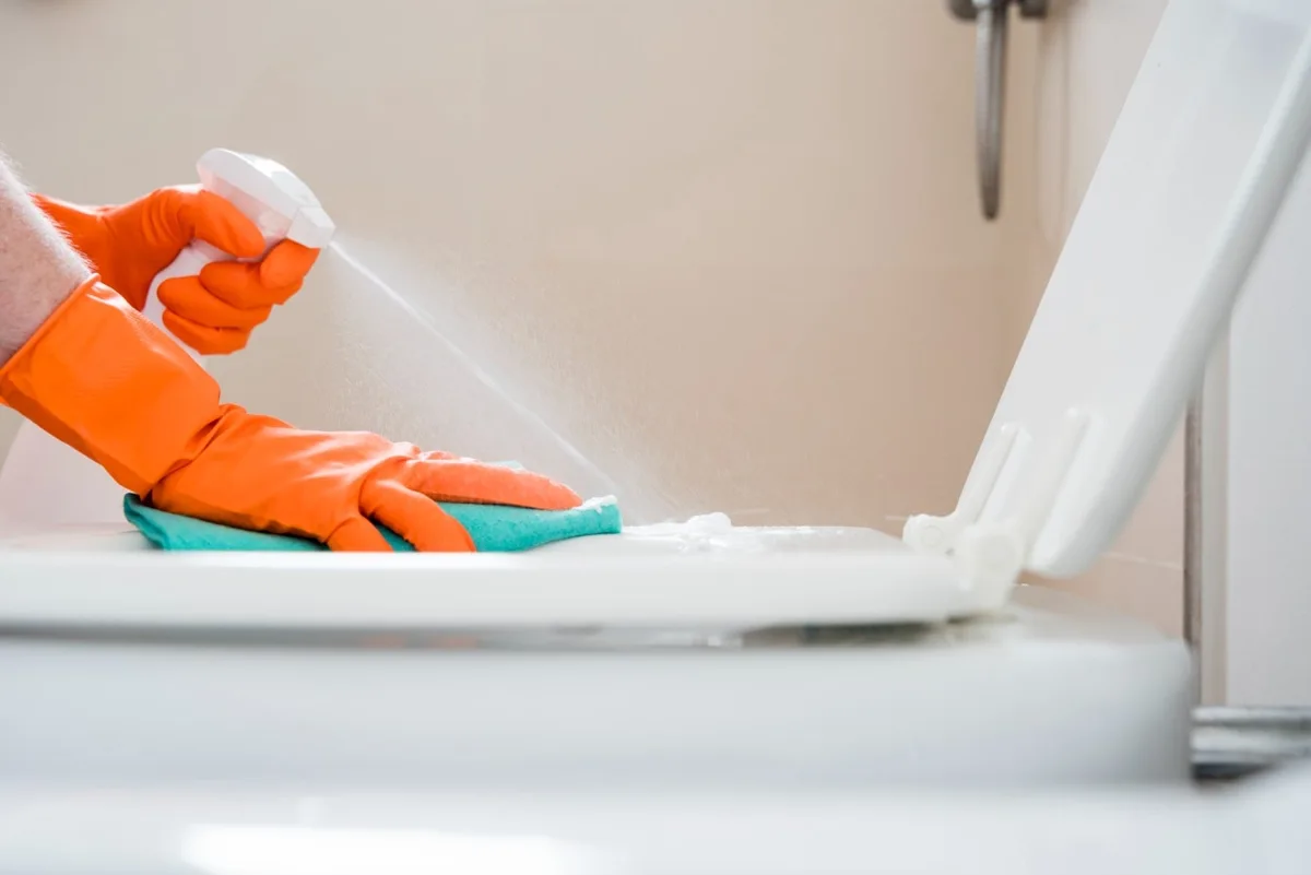 Gloved hands cleaning a restroom fixture