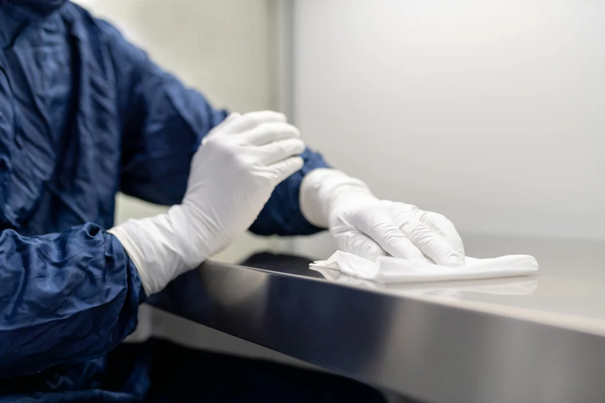 Gloved hands cleaning a commercial surface